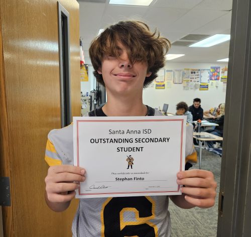 young boy with hair in face smiling and holding certificate